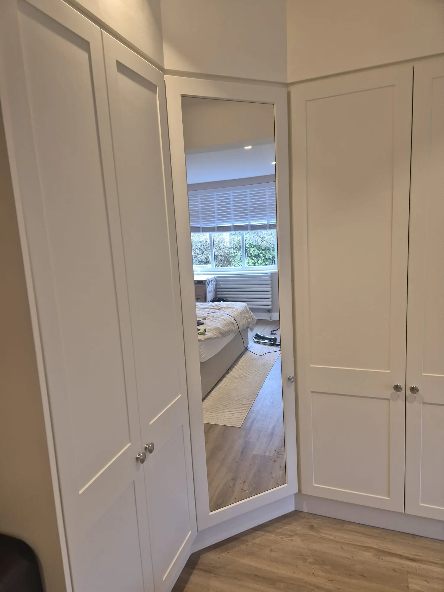 Full-height mirrored corner door between fitted wardrobe runs, fitted by CKC